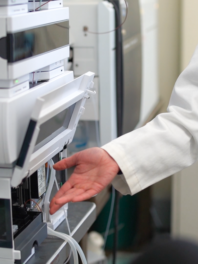 A hand gestures to a piece of scientific equipment.