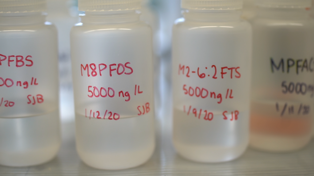 Clear plastic bottles labeled "M8PFOS 5000 ng/L 1/12/20 SJB" and M2-6:2 FTS 5000 ng/L 1/9/20 SJB".